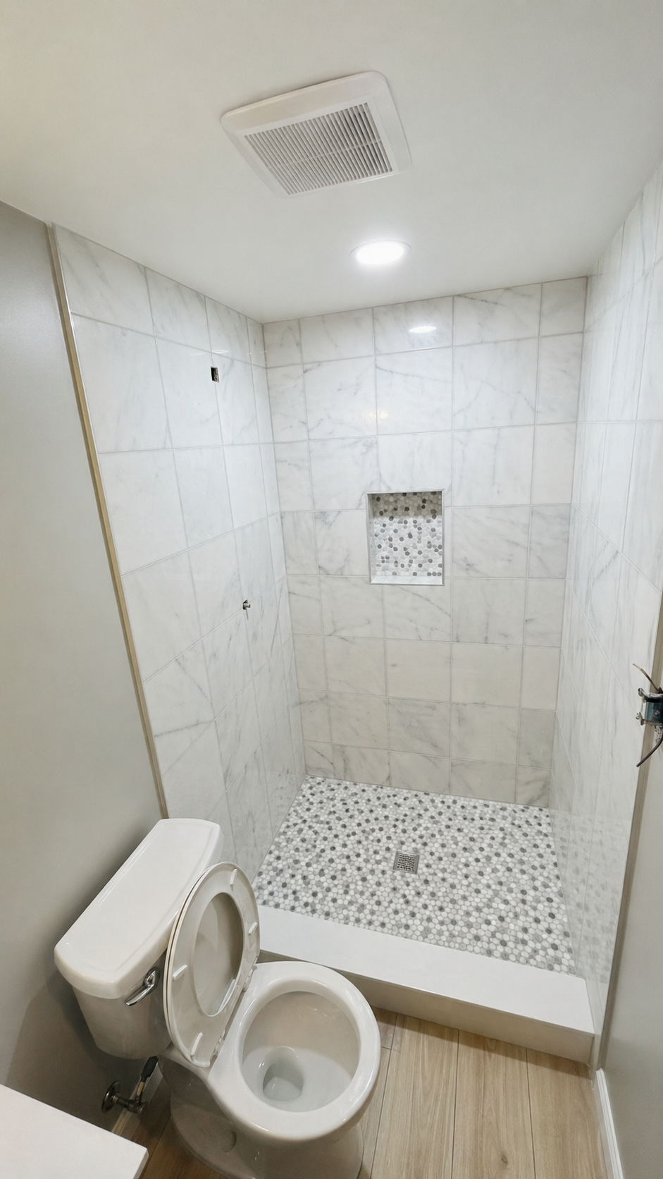 Finished bathroom shower with tile and ceiling vent