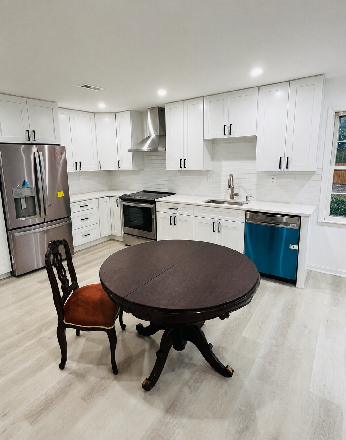 Kitchen after remodeling with white cabinets and modern vent